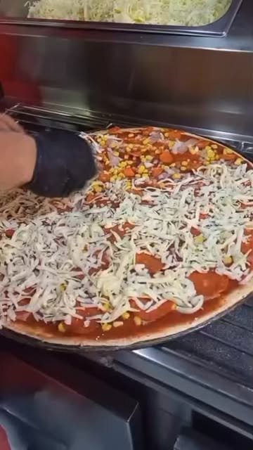 Pizza en preparación con salsa, queso y maíz