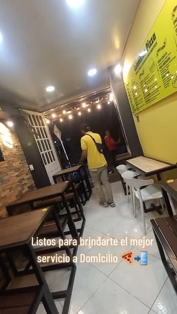Interior del local con mesas y paredes amarillas